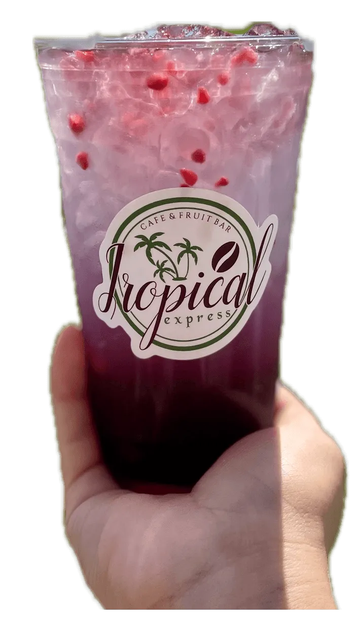 A hand holding a Tropical Express cup of Mermaid Breeze — a teal blueberry, pomegranate and raspberry drink made with coconut-berry Red Bull