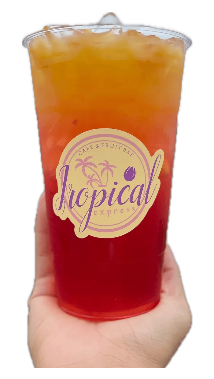 A hand holding a Tropical Express cup of Sunflower — a golden pomegranate, guava, grapefruit and peach drink topped with orange juice
